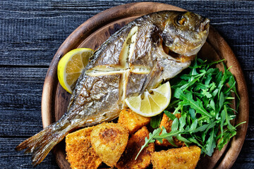 Whole roasted dorado fish with potato, top view