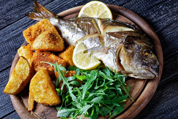 Whole roasted dorado fish with potato, top view