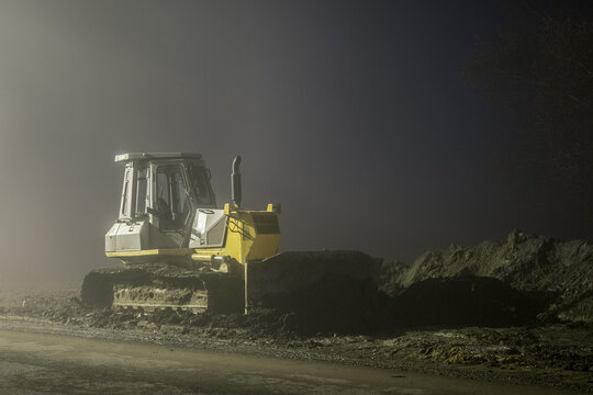 Blue excavator digger working at night on street
