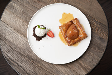 Puff pastry cake with caramel syrup, baked pear and ice cream