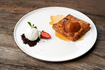 Puff pastry cake with caramel syrup, baked pear and ice cream