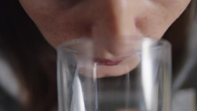close up of a woman taking a white zinc pill and drinking water