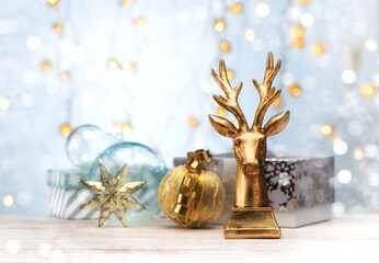 Fototapeta na wymiar Christmas or New Year postcard with golden deer, gift boxes and Christmas decorations on table. Festive still life with bokeh.