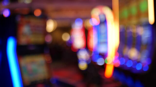 Defocused slot machines glow in casino on fabulous Las Vegas Strip, USA. Blurred gambling jackpot slots in hotel near Fremont street. Illuminated neon fruit machine for risk money playing and betting.