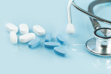 Medical background. white and blue capsule tablets or pills on the table with stethoscope. Close up. Healthcare pharmacy and medicine concept. Painkillers or prescription drugs consumption