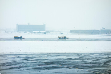 Snowstorm at an airport with trucks plowing snow