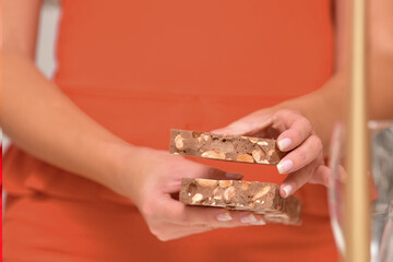 Close up of a delicious looking bar of traditional nougat being held by an out of focus female.