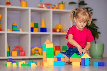 The girl plays with toys at home, in kindergarten or nursery. Child development.