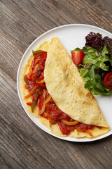 Omelette with vegetables on wooden background
