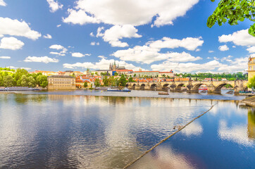 Fototapeta premium View of Prague old town, historical center with Prague Castle, St. Vitus Cathedral in Hradcany district, Charles Bridge Karluv Most, Vltava river, blue sky white clouds, Bohemia, Czech Republic