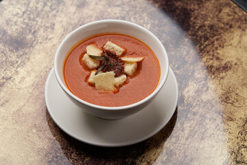 Bowl of tomato soup with cheese and bread.