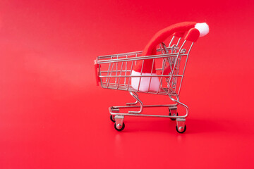 Merry Christmas with Miniature Santa Clause, Shopping cart on red background. Holiday, Celebration, technology, e-commerce, Black Friday, Cyber Monday and online payment concept