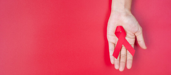 Hand holding Red Ribbon for supporting people living and illness. Healthcare and safe sex concept. December World Aids Day and multiple myeloma Cancer Awareness month