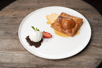 Puff pastry cake with caramel syrup, baked pear and ice cream
