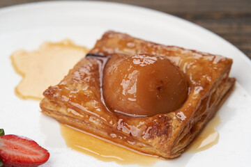 Puff pastry cake with caramel syrup, baked pear and ice cream