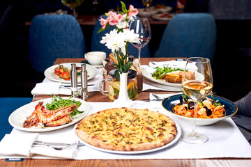Pizza, shrimps and other dishes on the table.