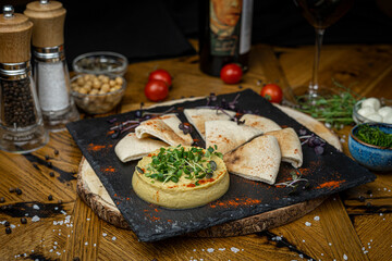 hummus served with pita on black plate 