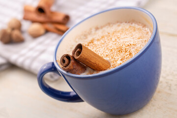 Blue cup of salep milky hot drink of Turkey with cinnamon powder and sticks healthy spice and autumn winter içeceği on white rustic vintage wooden table.
