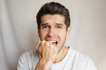 Portrait of a. young attractive guy with a super scared face expression biting his feast from fear 