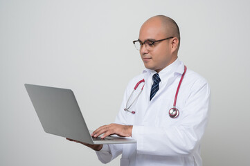 Physician in white coat, stethoscope working with laptop isolated on white.background.