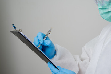 Close up A portrait of virologist put on PPE suit writing clipboard with pen isolated on white background. Personal Protective Equipment Concept..