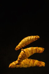 fresh homemade croissants levitate on a dark background. vertical orientation. creative food concept. moody artistic color image with copy space