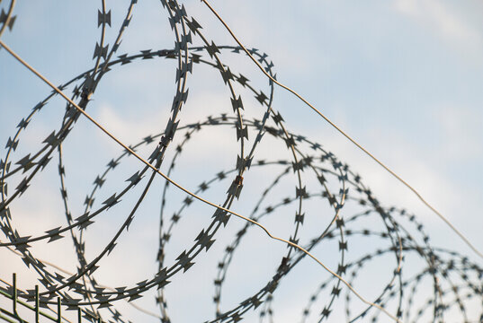 Barbed Wire Fence On European And World Border On Blue Sky Background Sunny Day, Closed Borders Concept