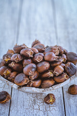 Raw chestnuts on a wooden background in an iron bowl. Rustic style