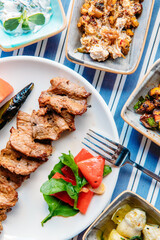Grilled meat, seafoods, meze, herbs, fish, raki, ouzo, appetizers and salads in Greek or Turkish Restaurant on the table for dinner or lunch at the beach from Greece or Turkey.