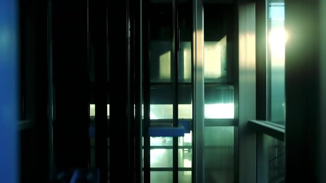 Modern glass elevator descending to the ground floor. Elevator going down.