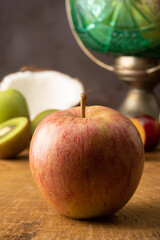 Apple in the foreground on rustic wood and fruits in the background, selective focus.