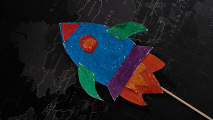 painted space rocket on black world map