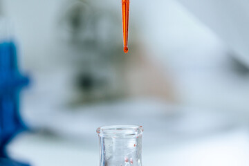 red liquid in a laboratory pipette on a blurry background.