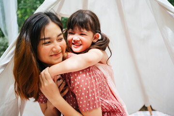 Asian mother and daughter piggy back outdoors at yard.
