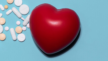 red heart, pills and dietary supplements on a blue background .