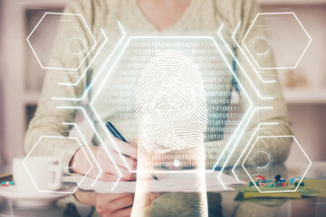 Blue fingerprint hologram over woman's hands taking notes background. Concept of protection. Double exposure