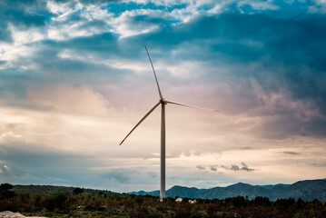 Fototapeta na wymiar Wind turbines on beautiful cloudy summer autumn sunset. Mountain landsape. Green ecological power energy generation. Wind farm eco field.