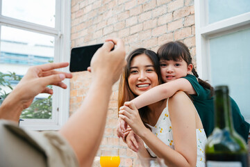 Mother and daughter taking photo with smartphone together at home.