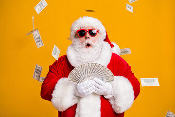 Portrait of his he nice attractive amazed stunned fat overweight bearded Santa holding in hand throwing usd 100 fan cash salary deposit isolated bright vivid shine vibrant yellow color background - obrazy, fototapety, plakaty