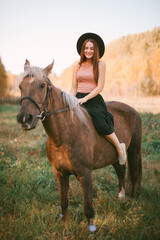 Fototapeta premium Girl in a hat riding a horse in nature.