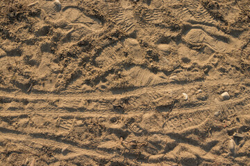 footprints of shoes and bicycle wheel on the sand, close up