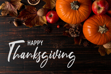 Thanksgiving greetings. Dry yellow leaves, pumpkins, berries, nuts and frame on wooden background, top view. Kaligraphic capital inscription.