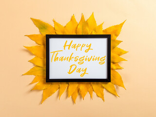 Thanksgiving greetings. Dry yellow leaves and frame on yellow background, top view. Kaligraphic capital inscription.