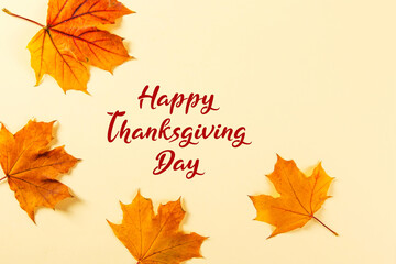 Thanksgiving greetings. Dry yellow leaves and frame on yellow background, top view. Kaligraphic capital inscription.