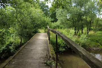Fototapeta na wymiar A rural bridge leads through the river to the village.