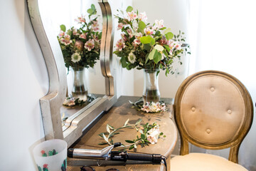 getting ready table with bridal bouquet, head wreath, curling iron and mirror