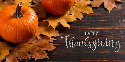 Thanksgiving greetings. Dry yellow leaves, pumpkins, berries, nuts and frame on a wooden background, top view. Kaligraphic capital inscription.