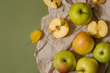 green and yellow apples,  whole and sliced, with autumn leaves on the table. Autumn composition top view