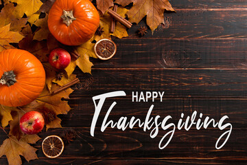 Thanksgiving greetings. Dry yellow leaves, pumpkins, berries, nuts and frame on a wooden background, top view. Kaligraphic capital inscription.