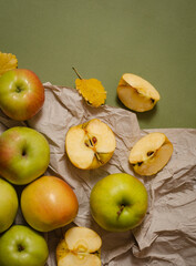 green and yellow apples,  whole and sliced, with autumn leaves on the table. Autumn composition top view